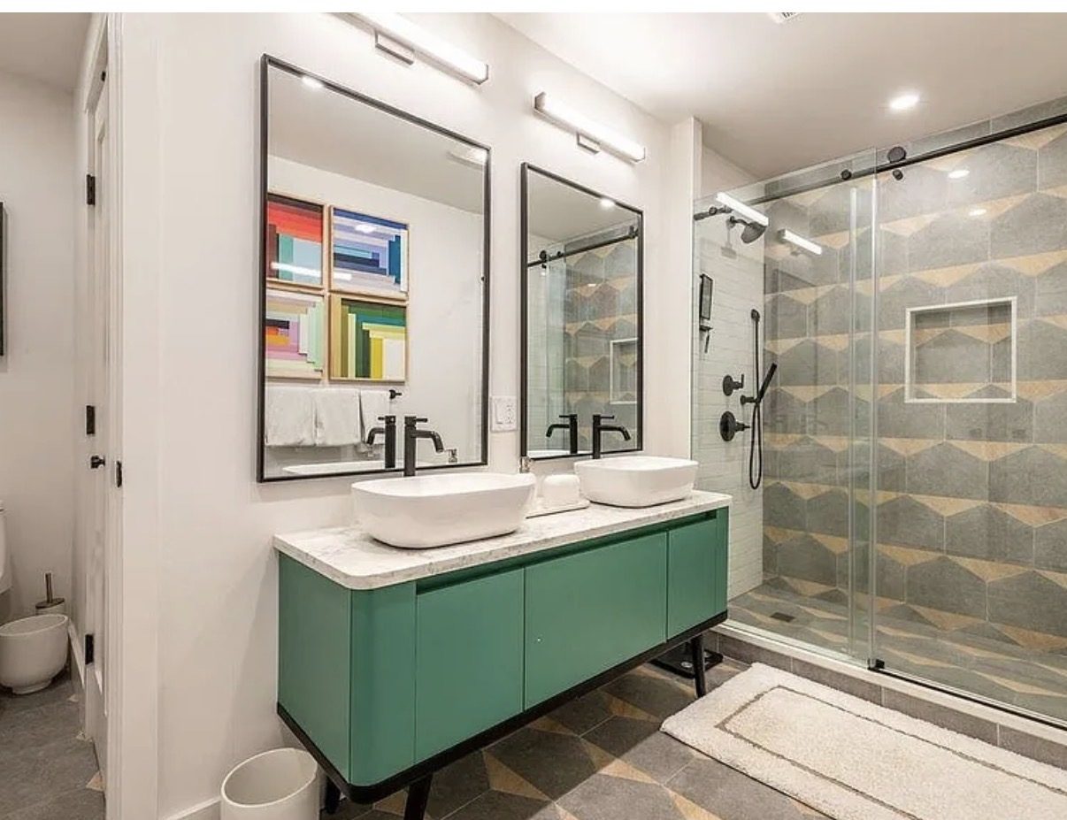 Primary bathroom with green vanity and glass shower